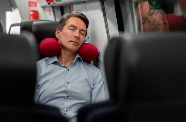 A person sleeping peacefully with his head resting comfortably on a neck support travel pillow