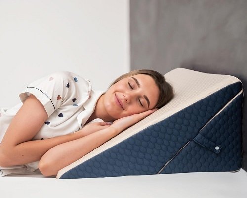 A woman using wedge pillow to alleviate acid reflux symptoms during sleep.